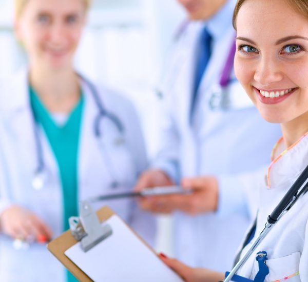 Attractive female doctor with folder in front of medical group .