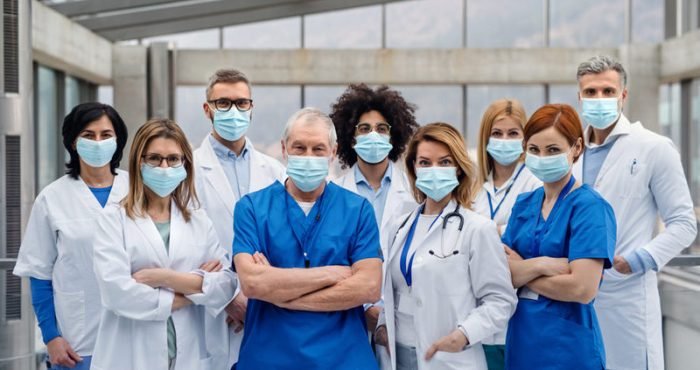 A group of doctors with face masks looking at camera, corona virus concept.